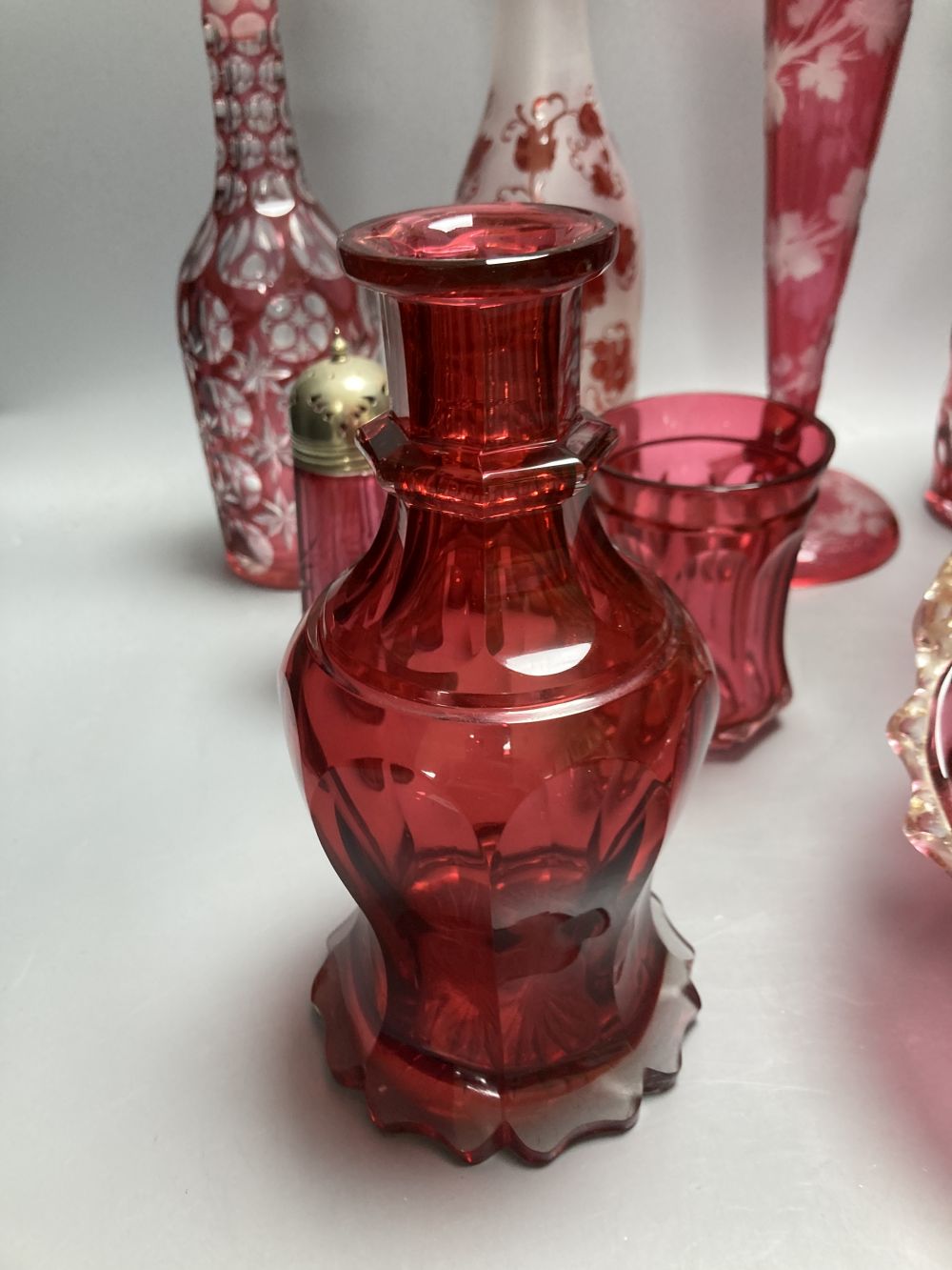 A collection of nine pieces of cranberry and ruby coloured glass, including a pair of decanters, two vases and a carafe and tumbler